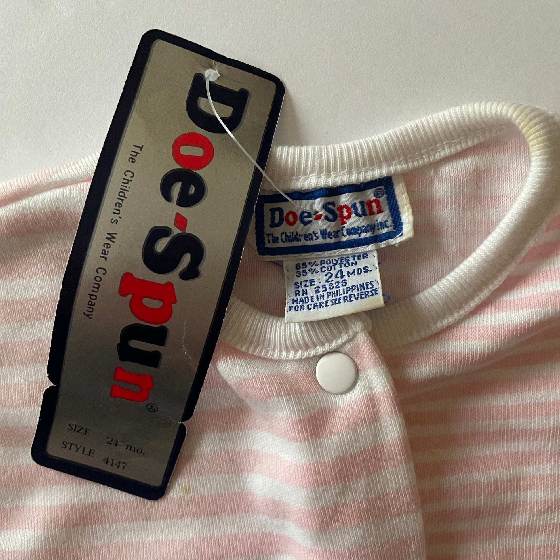 Tags showing the brand is size 24 mos, the make is polyester and cotton. 