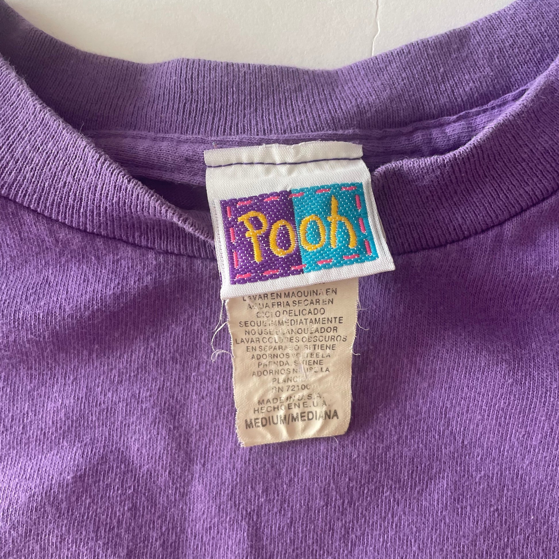 The tag showing it is Pooh branded, size medium, and made in the USA. 